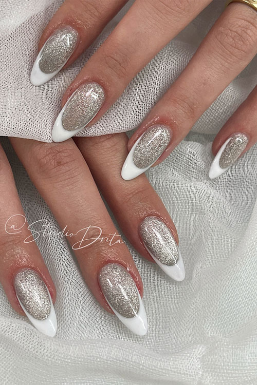 Long almond-shaped modern white French nails over a silver glitter base color