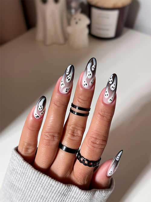 Long almond-shaped black ombre nails adorned with playful ghost designs, showcasing a spooky yet stylish aesthetic.