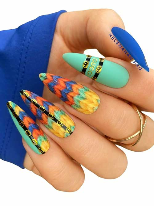 Matte green and blue almond-shaped nails adorned with sweater art in orange, yellow, and blue on three accent nails.