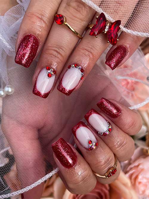 Short square bold red nails with glitter, featuring milky white French tips and rhinestones, perfect for Christmas.