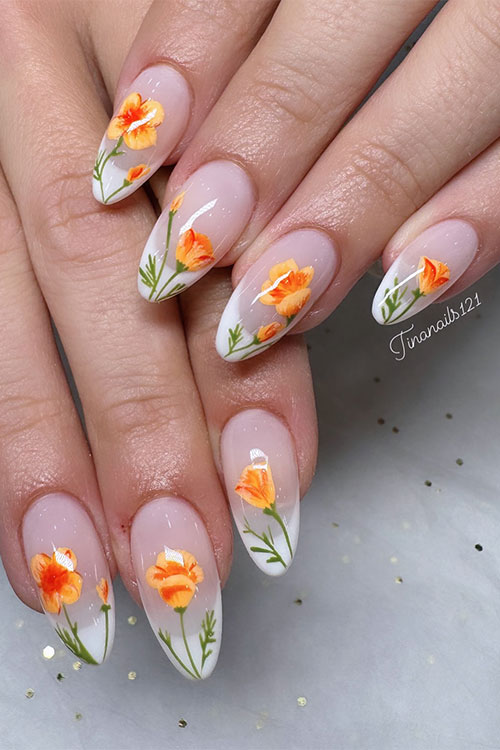 Long almond-shaped spring nails feature white French tips and orange flowers with green leaves