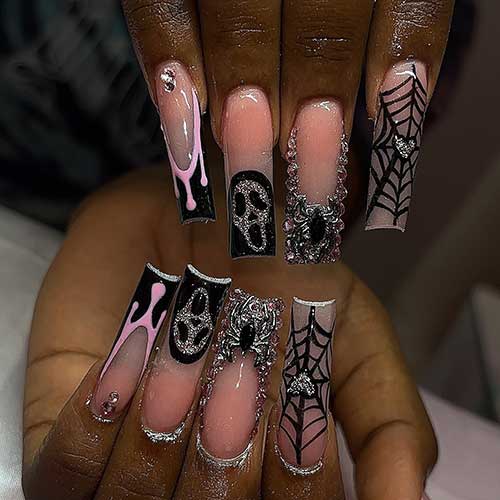 Long square nude Halloween nails featuring silver glitter, a scary face, black French tips, spider web,  and rhinestones