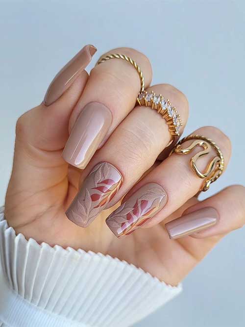 Long square sandy beige nails featuring two accent nails with sandy beige leaves over deep chestnut fall leaves.