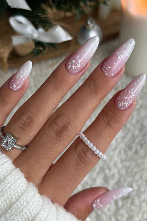 Elegant long almond-shaped Baby boomer nails featuring white snowflakes and dots, perfect for winter celebrations.