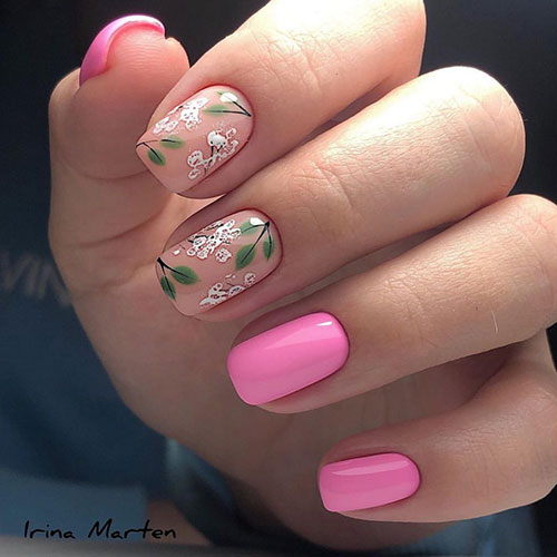 Candy pink short spring nails with two nude accent nails adorned with abstract white flowers and green leaves