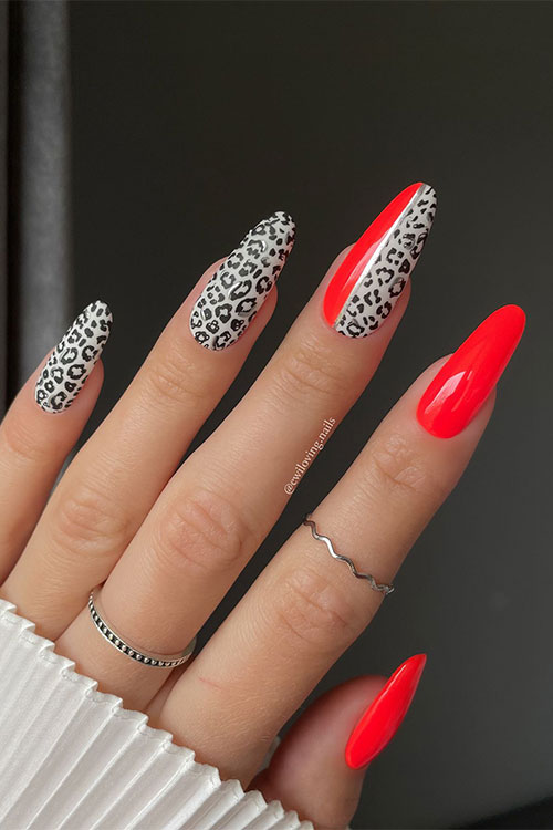 Long almond-shaped red and light grey nails adorned with black panther animal prints decorated with silver metallic