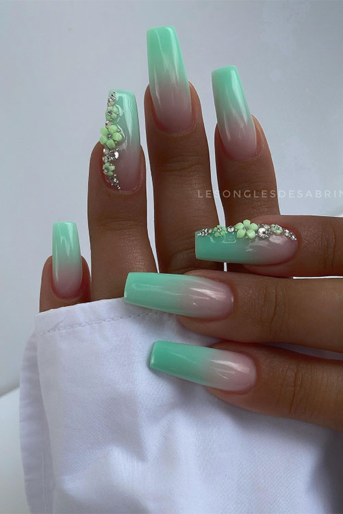 Long coffin-shaped green ombre nails with flowers and crystals on the ring fingernail