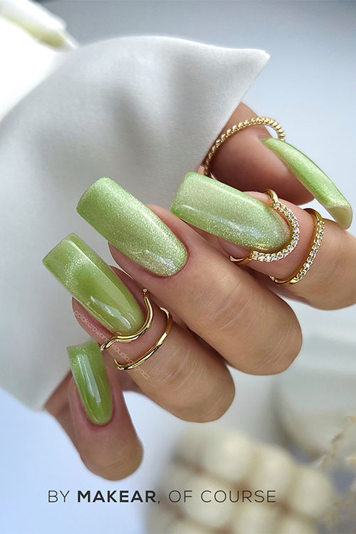 Long square-shaped shimmer green glow in the dark nails adorned with cat eye nail art design