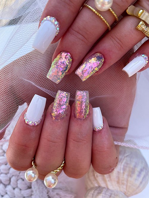 White cute summer nails with pearls and two accent clear nails adorned with encapsulated gold and pink foil flakes