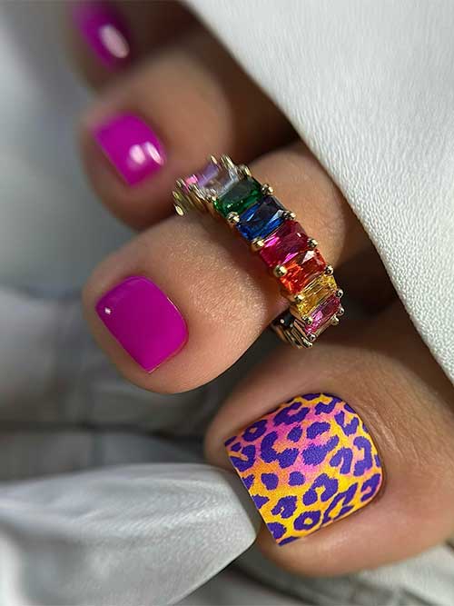 Magenta toenails with a big toenail decorated with a pedicure wrap feature purple leopard prints over a yellow base color