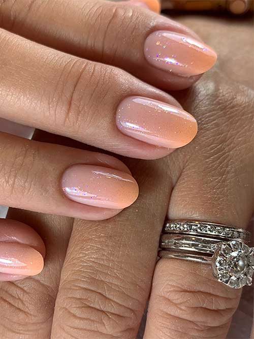 Short light orange summer ombre nails with a touch of glitter