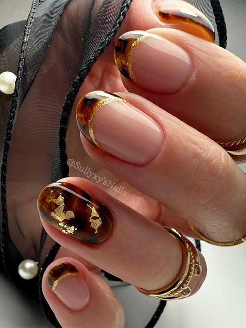 Almond-shaped tortoise shell nails embellished with gold glitter, including an accent nail decorated with gold foil.