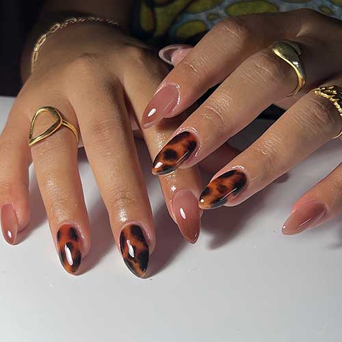 Almond-shaped tortoise shell nails complemented by two dark nude accent nails for a stylish manicure.