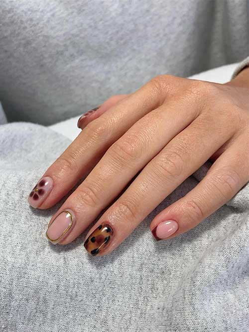 Classy short nude nails adorned with tortoise and snake prints, floral motifs, French tips, and gold 3D gel embellishments