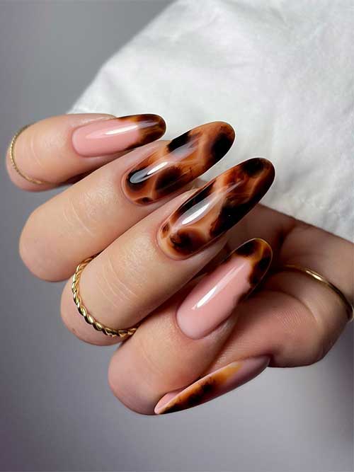 Glossy long almond-shaped tortoise nails featuring elegant French tips, showcasing a stylish and sophisticated manicure.