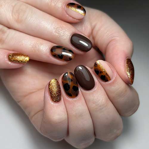 Glossy short tortoise nails adorned with shimmering gold glitter for a stylish and elegant look.