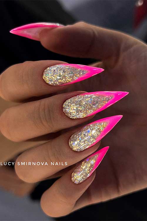 Long stiletto V-shaped hot pink sparkling French nails over a gold glitter base color