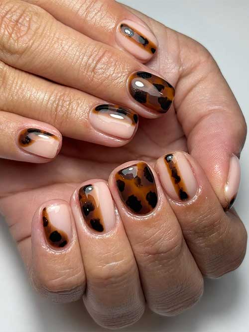 Stylish short tortoise shell nails with creative negative space patterns, perfect for a trendy and fashionable look.