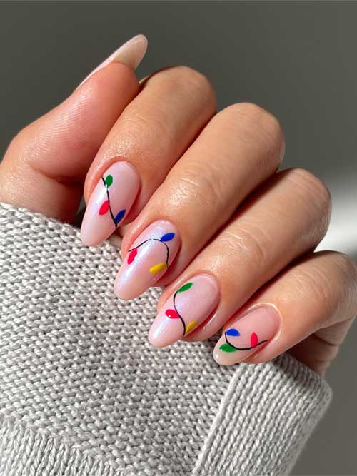 Festive Christmas lights nail art on a nude base, showcasing vibrant blue, red, green, and yellow colors.