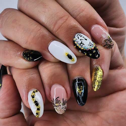 Almond-shaped New Year nails in black, white, and gold, featuring a nude accent nail with black and white fireworks design.