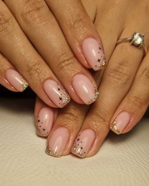 Cute short New Year nails with diagonal gold glitter French tips and dark brown stars on a nude base.