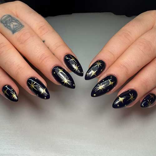 Elegant almond-shaped black nails featuring shimmering gold stars, ideal for New Year festivities.