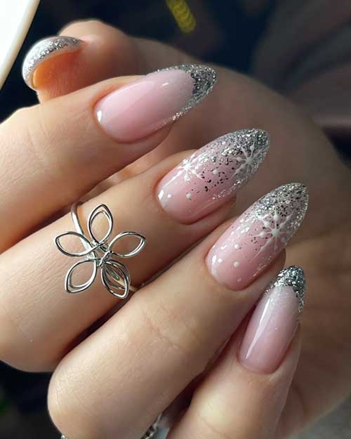 Elegant silver glitter French nails on a nude base, with two ombre accent nails decorated with snowflakes and white dots.