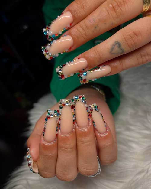 Long square-shaped nude nails adorned with colorful rhinestones and white pearls, perfect for New Year celebrations.