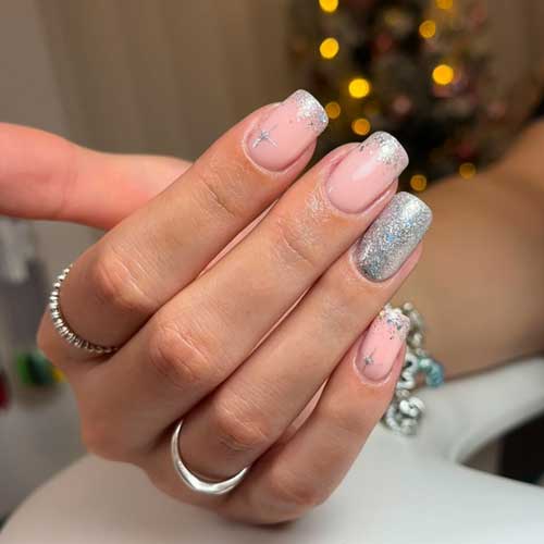 Silver glitter French nails over a nude base color with star nail art and an accent silver glitter nail.