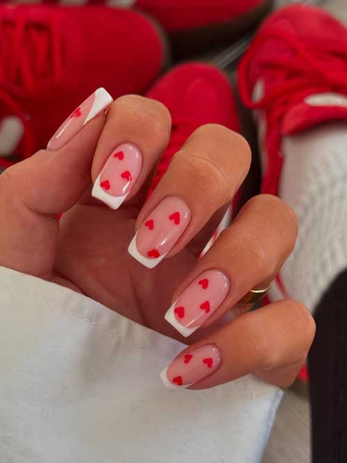 Classic white French manicure adorned with charming red hearts for a playful and romantic touch.