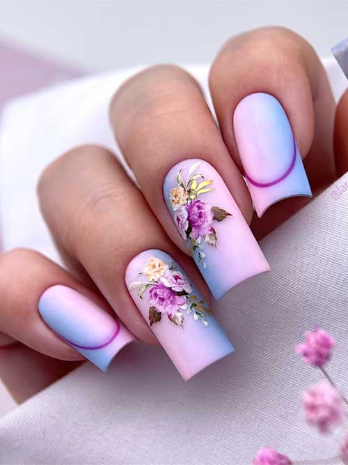 Beautiful gradient nails blend soft pink to light blue, with floral decals on ring and middle fingers, capturing spring's essence.