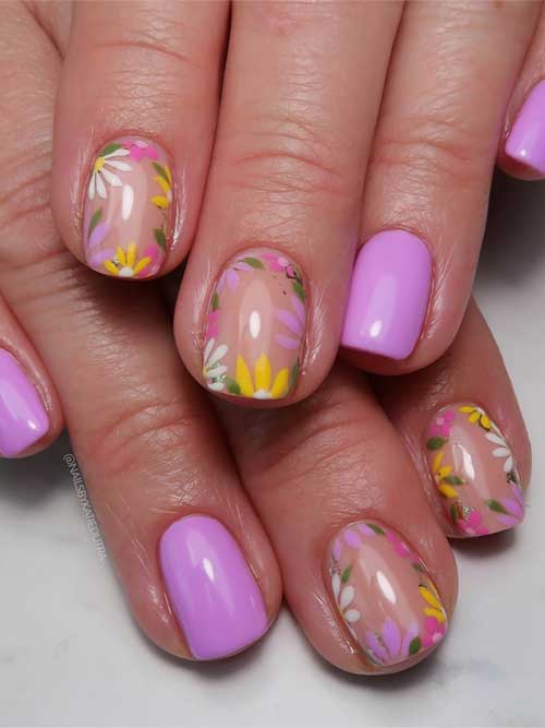 Delicate pastel purple nails adorned with vibrant floral designs, showcasing spring blooms in yellow, white, pink, and green