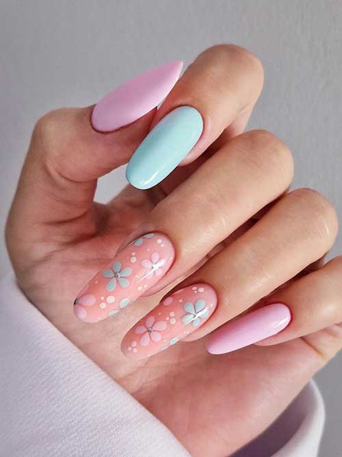 Pastel nails in pink, blue, and peach with floral patterns on ring and middle fingers, embodying spring's fresh essence.